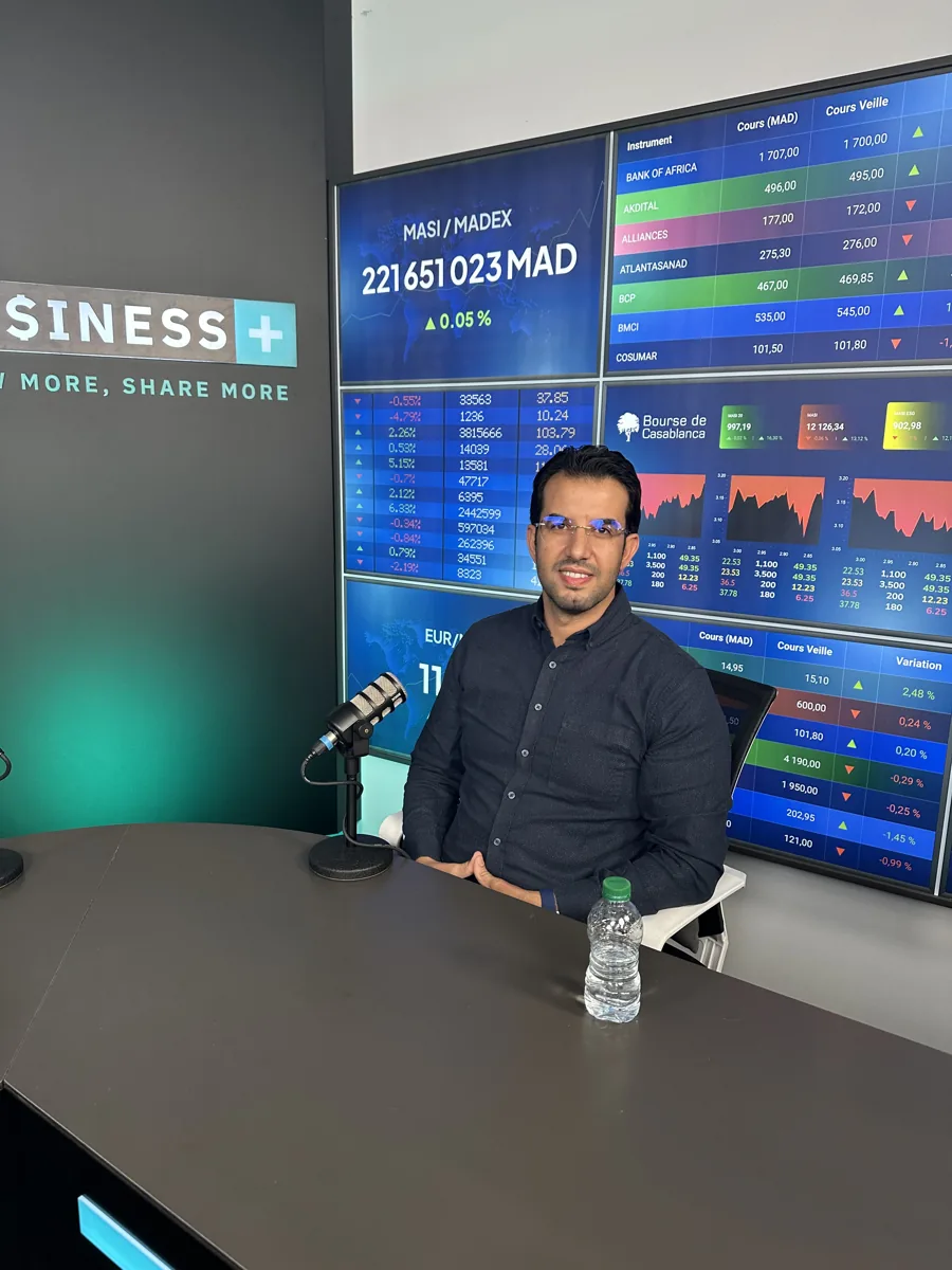 Abdelmajid Charrass sur le plateau de Business+, devant des écrans de cotations boursières