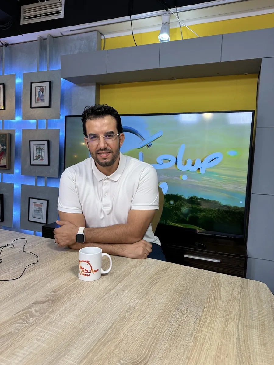 Dr CHARRASS Abdelmajid assise dans un plateau télévision en polo blanc.